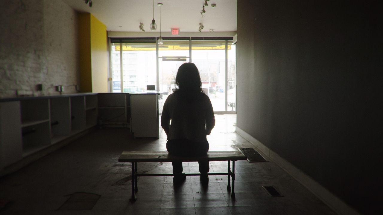 a woman sitting in the darkness on a bench